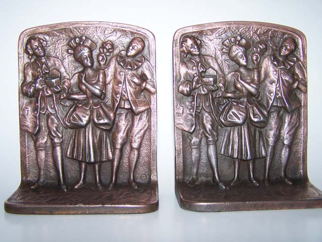 A pair of cast iron antique Bookends circa 1925 depicting three people going to a Colonial Ball